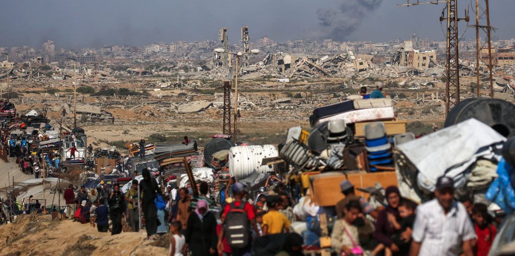Cartolina 62 – L’impossibile neutralità Displaced Palestinians move with their belongings southwards on a road in the Nuseirat refugee camp in the central Gaza Strip as smoke billows during Israeli strikes in Gaza City on September 14, 2025. (Photo by Eyad BABA / AFP)